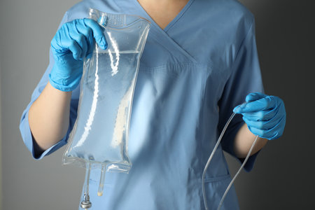 Nurse with IV infusion set on gray background, closeupの写真素材