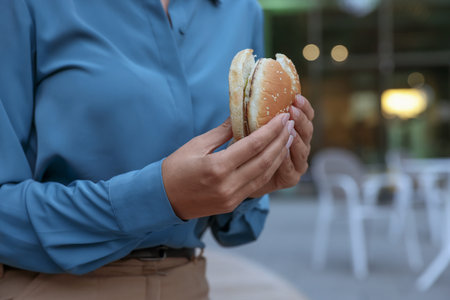Lunch time. Businesswoman with hamburger outdoors, closeup. Space for textの写真素材