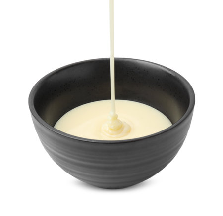 Pouring condensed milk into bowl isolated on whiteの写真素材