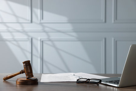 Gavel, papers, glasses and laptop on wooden table indoors. Judge workplaceの写真素材