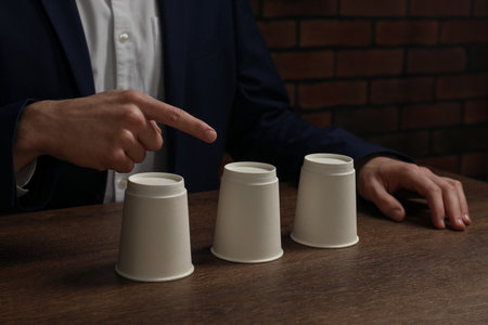 Man playing shell game at wooden table, closeupの写真素材