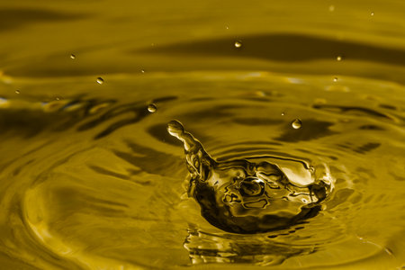 Splash of golden oily liquid with drops as background, closeupの写真素材