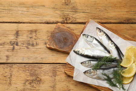 Fresh raw sprats, lemon and dill on wooden table, top view. Space for textの写真素材