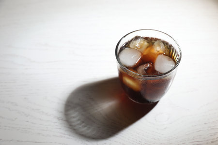 Refreshing iced coffee in glass on white wooden table. Space for textの写真素材