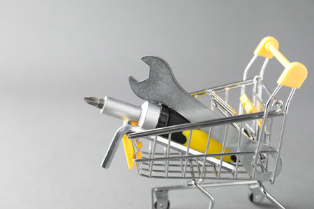 Small shopping cart with set of construction tools on gray background. Space for textの写真素材