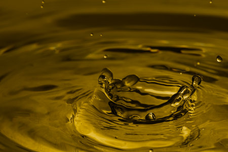 Splash of golden oily liquid with drops as background, closeupの写真素材