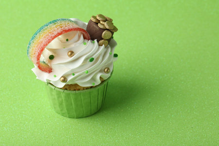 St. Patrick's day party. Tasty cupcake with sour rainbow belt and pot of gold toppers on green background. Space for textの写真素材