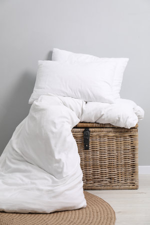 Soft pillows, duvet and wicker trunk indoorsの写真素材