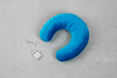 Soft travel pillow and earphones on gray textured background, top viewの写真素材