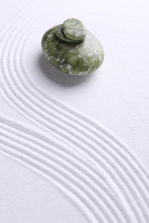 Zen garden stones on white sand with pattern. Space for textの写真素材