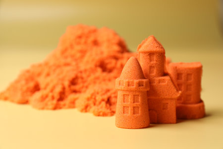 Castle figures made of orange kinetic sand on beige background, closeup. Space for textの写真素材