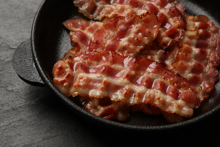 Fried bacon slices on dark textured table, closeupの写真素材