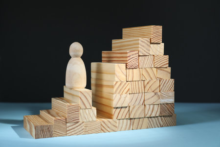 Stairs of blocks with gap as barrier and wooden human figure on light blue surface. Path to growth and successの写真素材