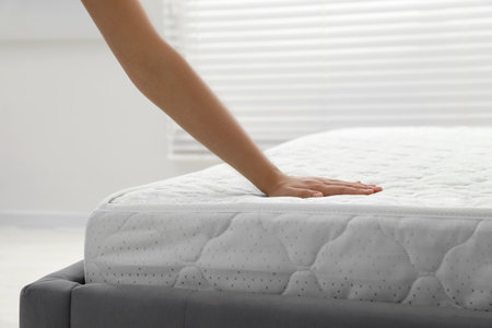 Woman touching soft light green mattress indoors, closeupの写真素材