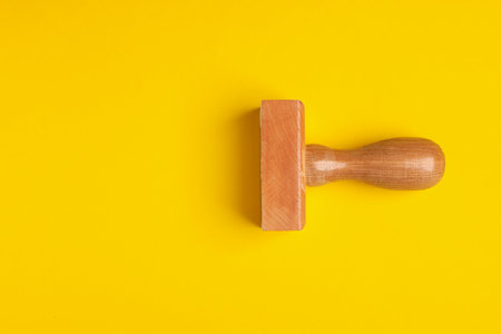 One wooden stamp tool on yellow background, top view. Space for textの写真素材