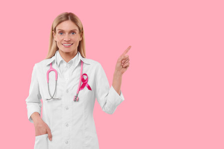 Doctor with pink ribbon and stethoscope on color background, space for text. Breast cancer awarenessの写真素材