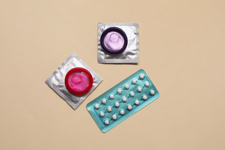 Contraception choice. Pills and condoms on beige background, flat layの写真素材
