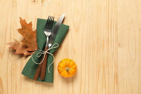 Napkin, cutlery and pumpkin on light wooden background, flat lay with space for text. Stylish autumn table settingの写真素材