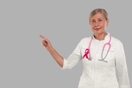 Doctor with pink ribbon and stethoscope on light gray background, space for text. Breast cancer awarenessの写真素材