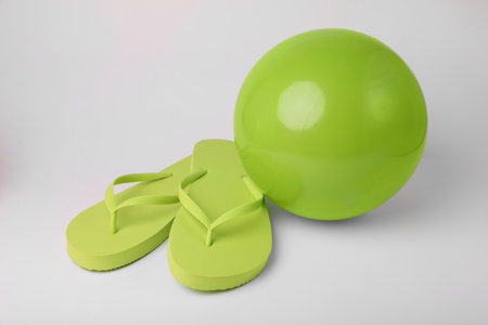 Green inflatable beach ball and flip flops on white backgroundの写真素材