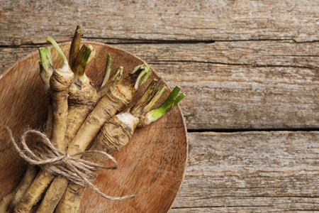 Bunch of fresh horseradish roots on wooden table, top view. Space for textの写真素材