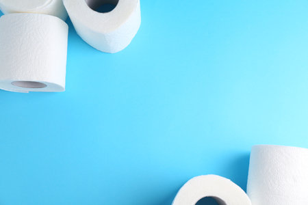 Soft toilet paper rolls on light blue background, flat lay. Space for textの写真素材
