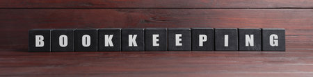 Word Bookkeeping made with black cubes on wooden table. Space for textの写真素材