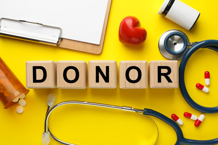 Flat lay composition with wooden cubes with the word Donor on yellow backgroundの写真素材
