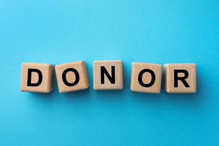 Wooden cubes with word Donor on light blue background, flay layの写真素材