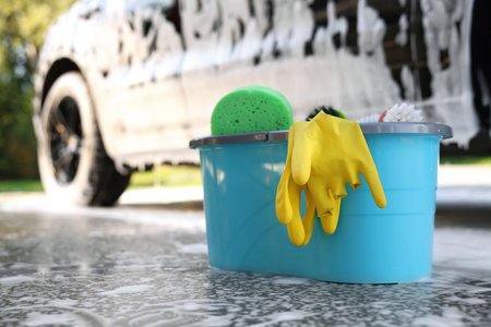 Car cleaning supplies and auto covered with foam outdoorsの写真素材