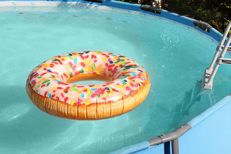 Inflatable ring floating on water in above ground swimming pool outdoors