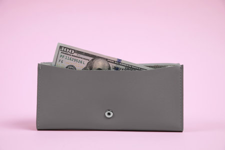 Stylish gray leather purse with dollar banknote on pink backgroundの写真素材