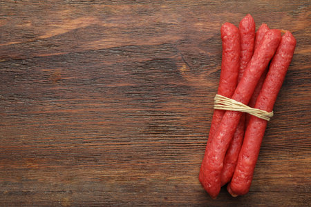 Many thin dry smoked sausages on wooden table, top view. Space for textの写真素材