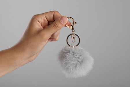 Woman holding fur keychain on gray background, closeupの写真素材