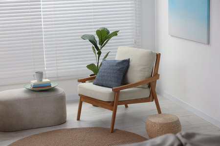 Comfortable beige armchair, ottoman and houseplant in living room. Interior designの写真素材