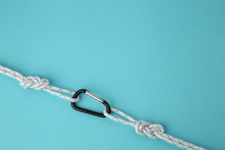 One metal carabiner with ropes on light blue background, top view. Space for textの写真素材