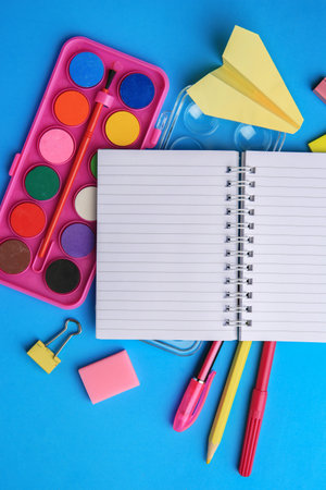 Flat lay composition with blank notebook and other school stationery on light blue background, space...