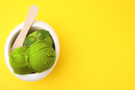Tasty matcha ice cream in bowl on yellow background, top view. Space for textの写真素材