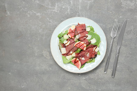 Plate with delicious bresaola salad served on gray textured table, flat lay. Space for textの写真素材