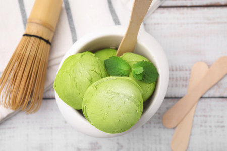 Tasty matcha ice cream in bowl on white wooden table, flat layの写真素材