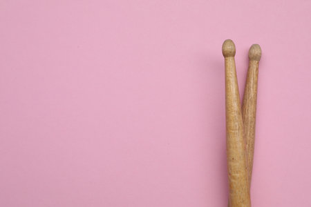 Two wooden drum sticks on pink background, top view. Space for textの写真素材