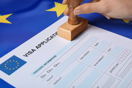 Immigration to European Union. Woman stamping visa application form on flag, closeupの写真素材