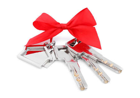 Keys with keychain in shape of house and red bow isolated on whiteの写真素材