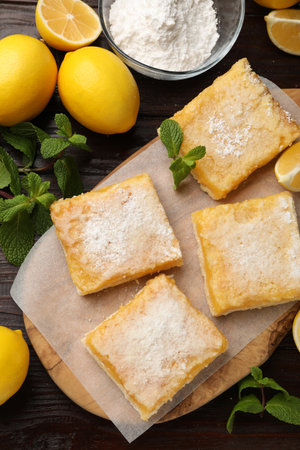 Tasty lemon bars with powdered sugar and mint on wooden table, flat layの写真素材