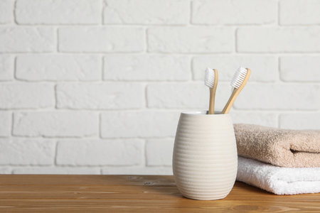 Bamboo toothbrushes in holder and towels on wooden table. Space for textの写真素材