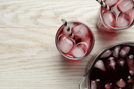 Delicious iced hibiscus tea on white wooden table, flat lay. Space for textの写真素材