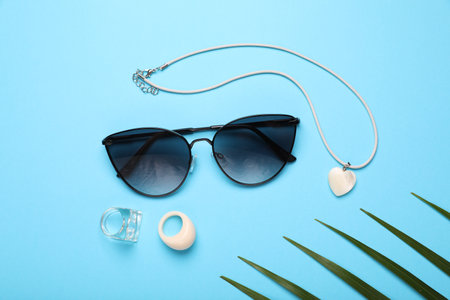 Flat lay composition with stylish sunglasses and accessories on light blue backgroundの写真素材