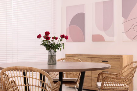 Chairs and table with vase of red rose flowers in dining room. Stylish interiorの写真素材