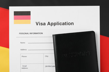 Immigration to Germany. Visa application form and passport on flag, top viewの写真素材