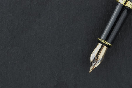 Stylish fountain pen on dark textured table, top view. Space for textの写真素材